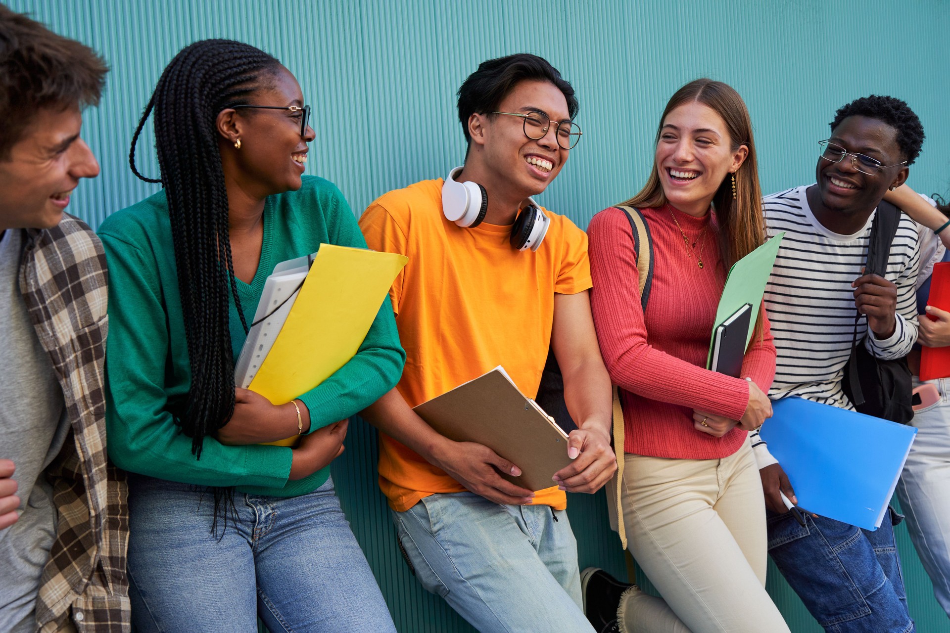 Happy group of multiracial students gathering having fun, talking and laughing after school.